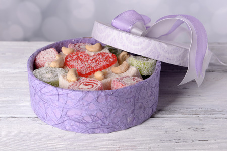 Present box with sweets on table on bright background