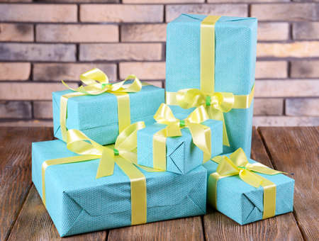 Beautiful gifts on table on brick wall background