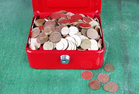 Rectangular red open suitcase with Ukrainian coins on wooden tableの写真素材
