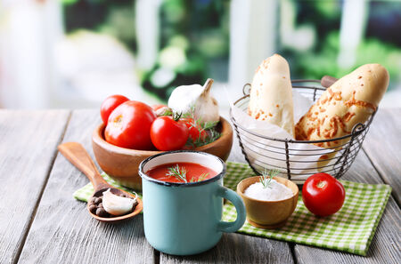 Homemade tomato juice in color mug, bread sticks, spices and fresh tomatoes on wooden table, on brightの写真素材