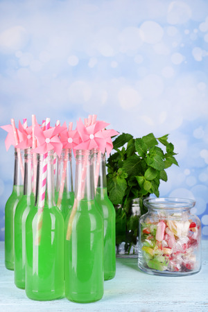 Bottles with drink and sweets on table on bright backgroundの写真素材