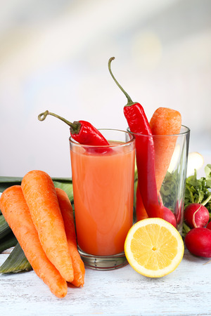 Glass of fresh carrot juice with vegetables on wooden tableの写真素材