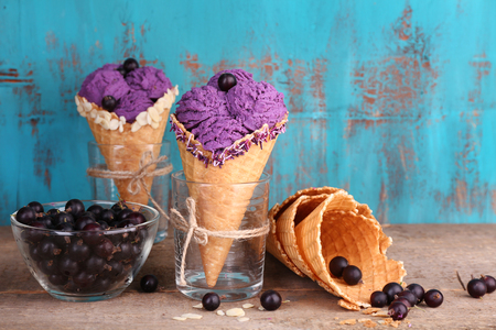 Tasty ice cream with berries in waffle cones on blue wooden backgroundの写真素材