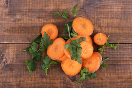 Slices of carrot and parsley on wooden backgroundの写真素材