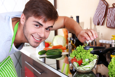Handsome man cooking in kitchen at homeの写真素材