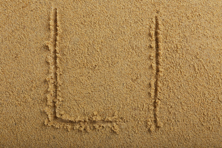 Alphabet letter written on wet beach sandの写真素材
