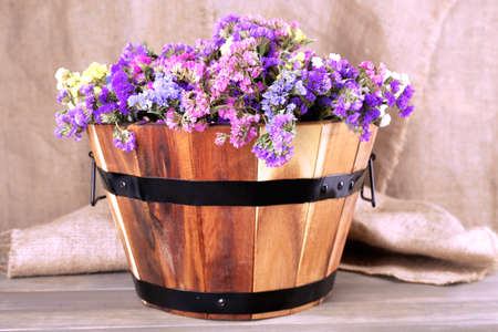 Big wooden basket with fresh flowers on sacking backgroundの写真素材