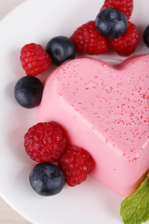 Heart shaped cake with berries on plate on wooden backgroundの写真素材
