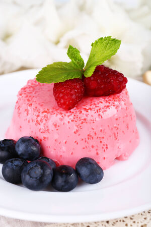 Round shaped cake with berries on plate on lace napkin on wooden backgroundの写真素材