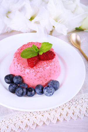 Round shaped cake with berries on plate on lace napkin on wooden backgroundの写真素材