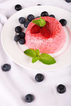 Round shaped cake with berries on plate on table clothの写真素材