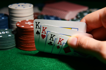 Chips and cards for poker in hand on green tableの写真素材