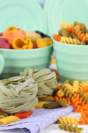 Colorful pasta in color bowls and mugs on wooden backgroundの写真素材