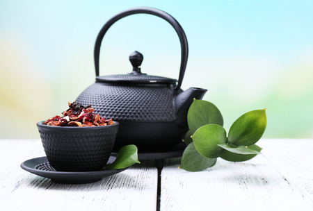 Black teapot, bowl and tea on color wooden table, on bright backgroundの写真素材