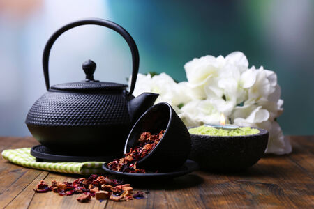 Black teapot, bowl and hibiscus tea on color wooden table, on bright backgroundの写真素材