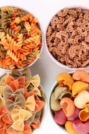Assortment of colorful pasta in color bowls isolated on whiteの写真素材