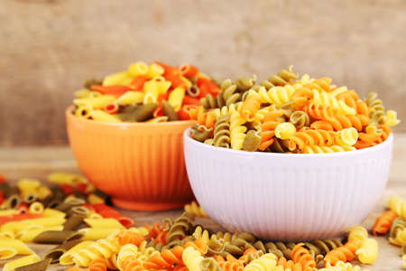 Assortment of colorful pasta in color bowls on wooden backgroundの写真素材