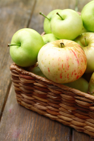 Ripe apples in basket on wooden table close-upの写真素材