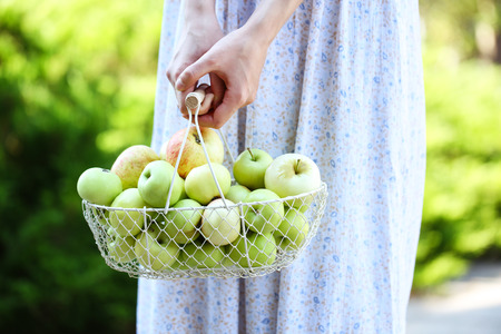 Girl holding basket of apples outdoorsの写真素材