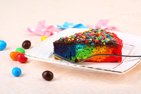 Delicious rainbow cake on plate, on tablecloth backgroundの写真素材