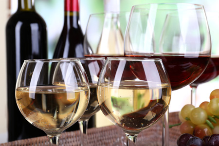Bottles and glasses of wine and ripe grapes on table on natural backgroundの写真素材