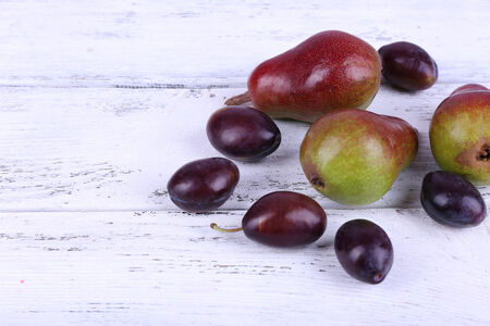 Beautiful ripe pears and plums on wooden table close-upの写真素材