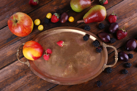 Different berries and fruits on tray on wooden table close-upの写真素材