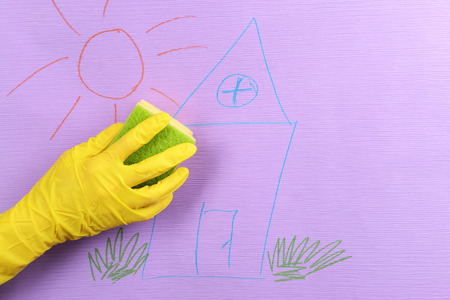 Hand in glove wiping children drawing on wallpaperの写真素材