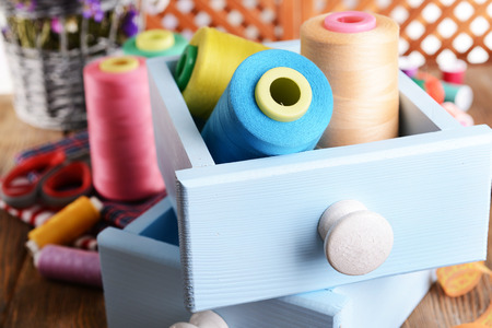 Sewing Accessories in wooden boxes on table on brown background