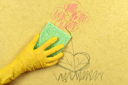 Hand in glove wiping children drawing on wallpaperの写真素材