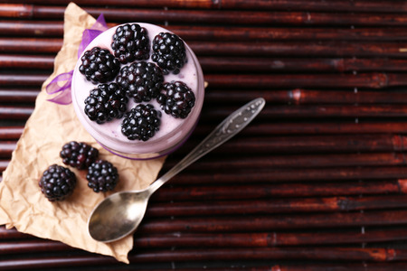 Healthy breakfast - yogurt with  blackberries and muesli served in glass jar, on dark  backgroundの写真素材