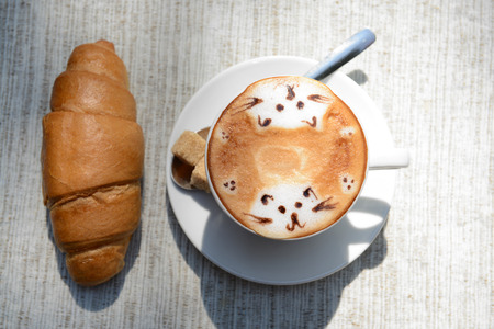 Cup of coffee with cute drawing on table, close upの写真素材