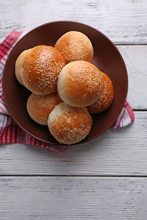 Tasty buns with sesame on plate, on color wooden backgroundの写真素材