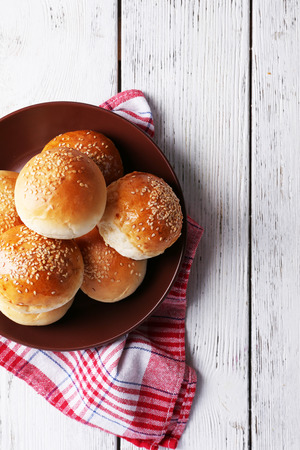 Tasty buns with sesame on plate, on color wooden backgroundの写真素材