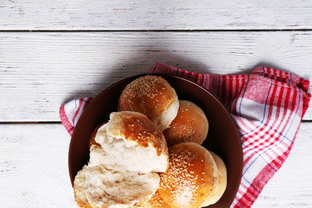 Tasty buns with sesame on plate, on color wooden backgroundの写真素材