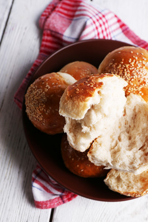 Tasty buns with sesame on plate, on color wooden backgroundの写真素材