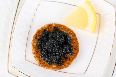 Black caviar on crispy bread on plate closeupの写真素材