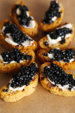 Slices of bread with butter and black caviar on paper backgroundの写真素材