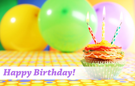Delicious birthday cupcake on table on bright backgroundの写真素材