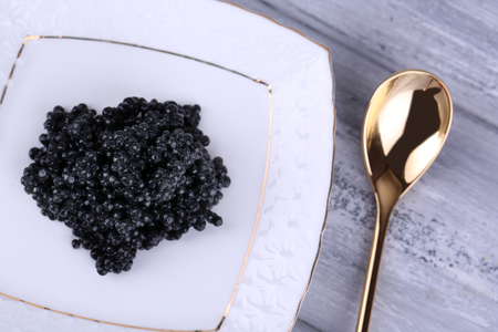 Black caviar on plate on grey wooden backgroundの写真素材