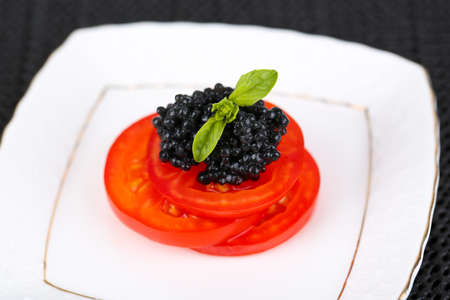 Slices of tomato with black caviar on plate closeupの写真素材