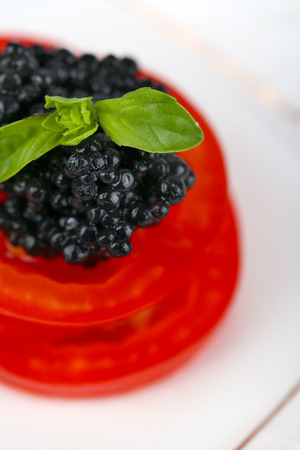 Slices of tomato with black caviar on plate closeupの写真素材