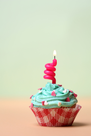 Delicious birthday cupcake on table on light backgroundの写真素材