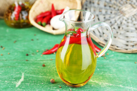 Homemade natural infused olive oil with red chili peppers on color wooden backgroundの写真素材