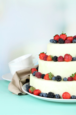 Beautiful wedding cake with berries on wooden table, on light backgroundの写真素材