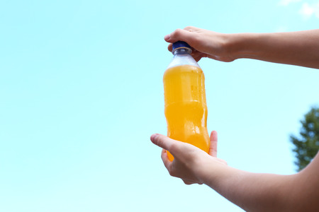 Hand opening bottle with sweet water on sky backgroundの写真素材