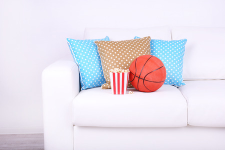 Popcorn and basketball on sofa in roomの写真素材