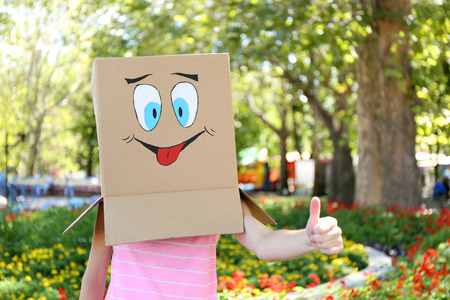 Woman with cardboard box on her head with happy face, outdoorsの写真素材