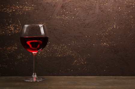 Glass of red wine on wooden table on wooden wall backgroundの写真素材