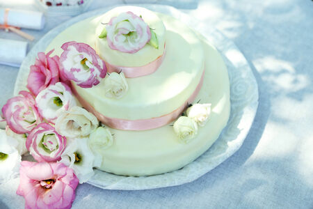 Beautiful wedding cake with flowers on table, outdoors